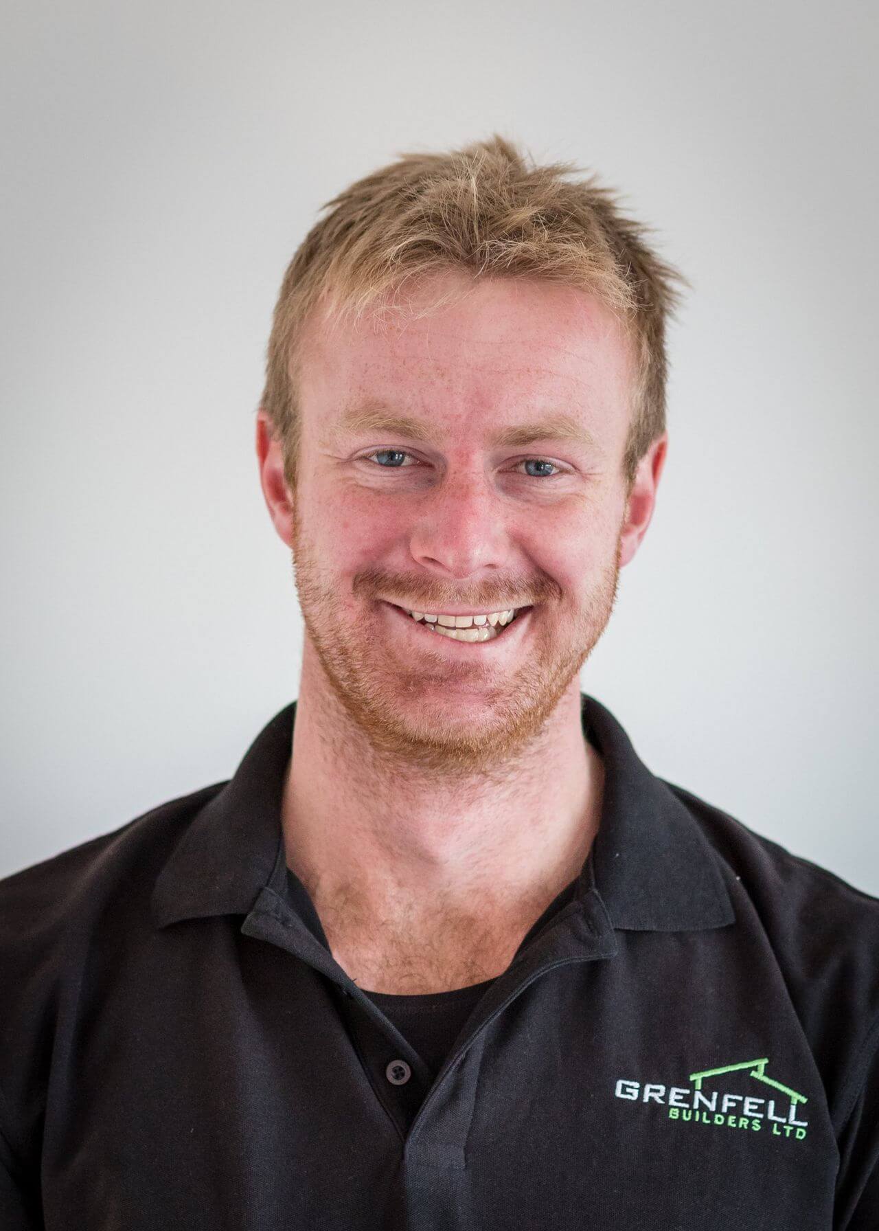 a man with a beard is wearing a black shirt and smiling .