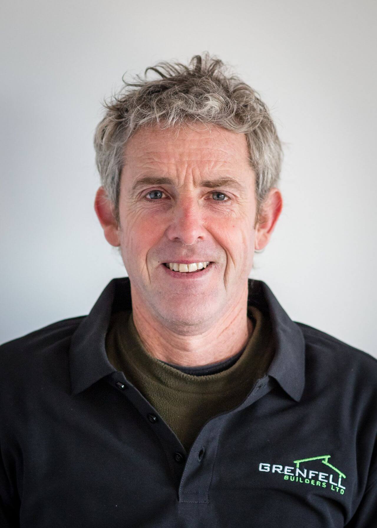 a man with gray hair is wearing a black shirt and smiling .