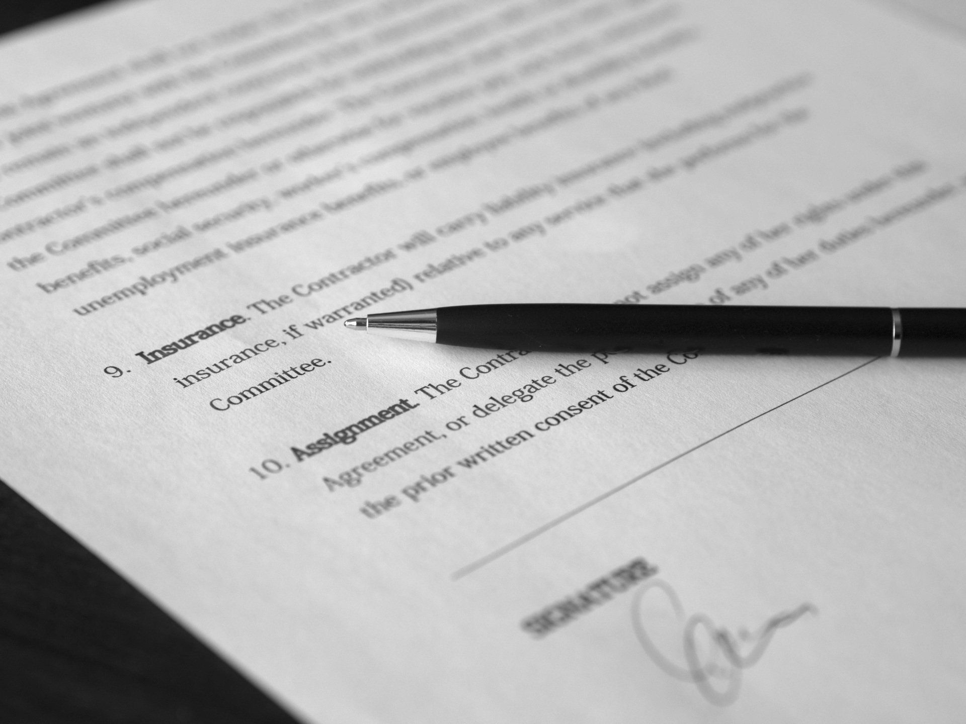 Black pen resting on a signed document with blurred text and signature visible.
