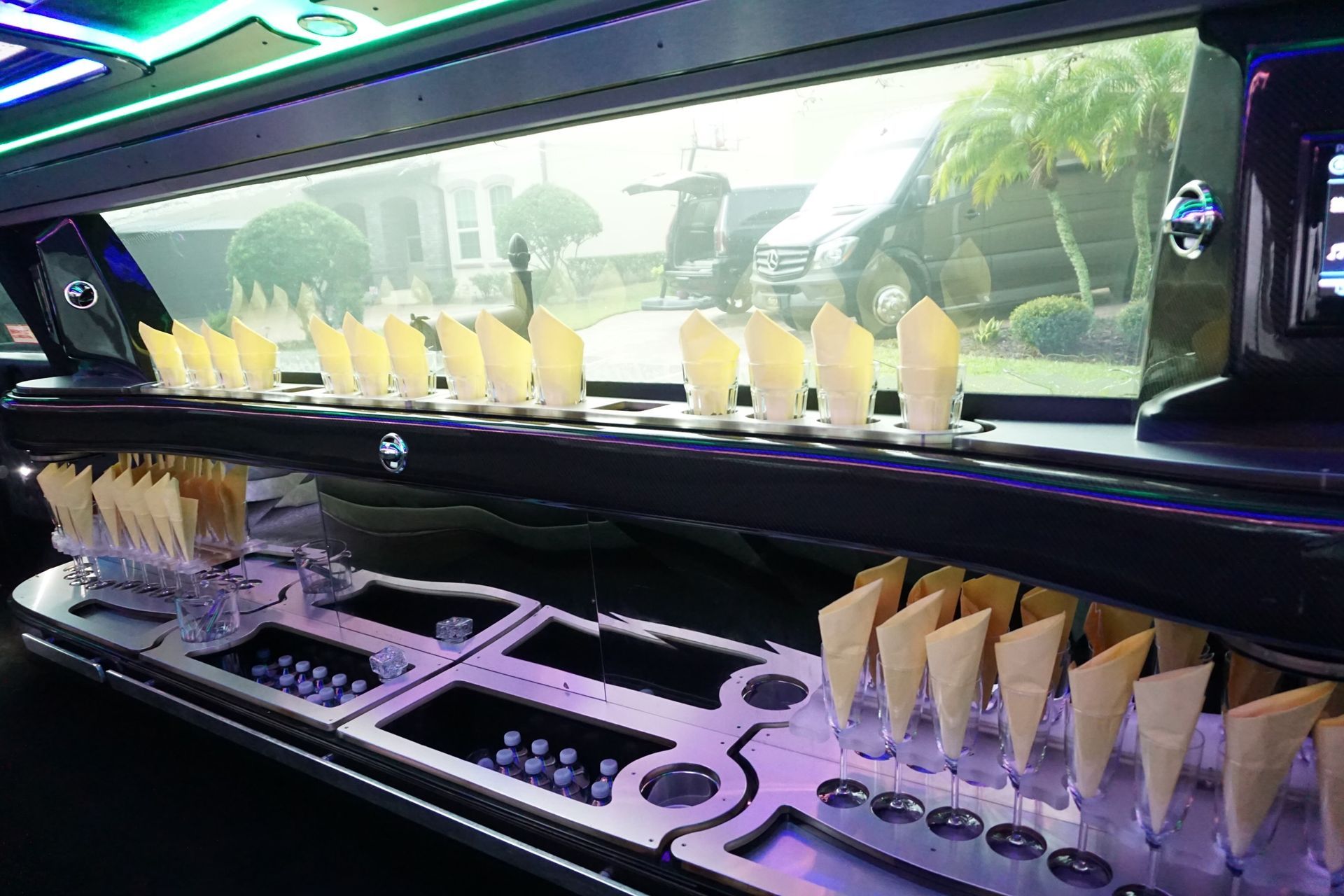 Interior of a limousine with lit drink glasses; outdoor scene visible through the window. Exotic Limo Orlando