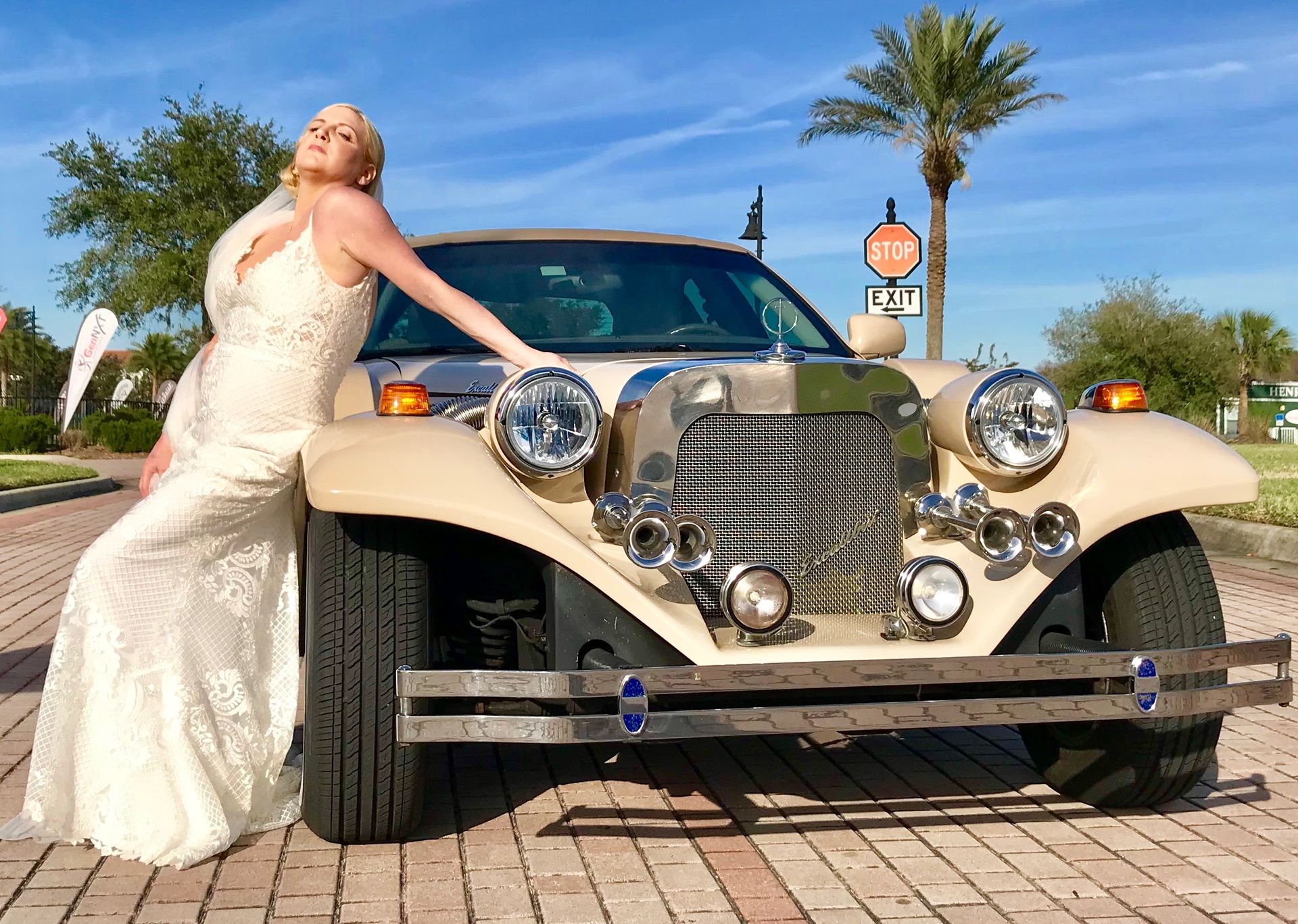 Exotic Limo Orlando Woman in wedding dress leans on a vintage-style car in a sunny outdoor setting.