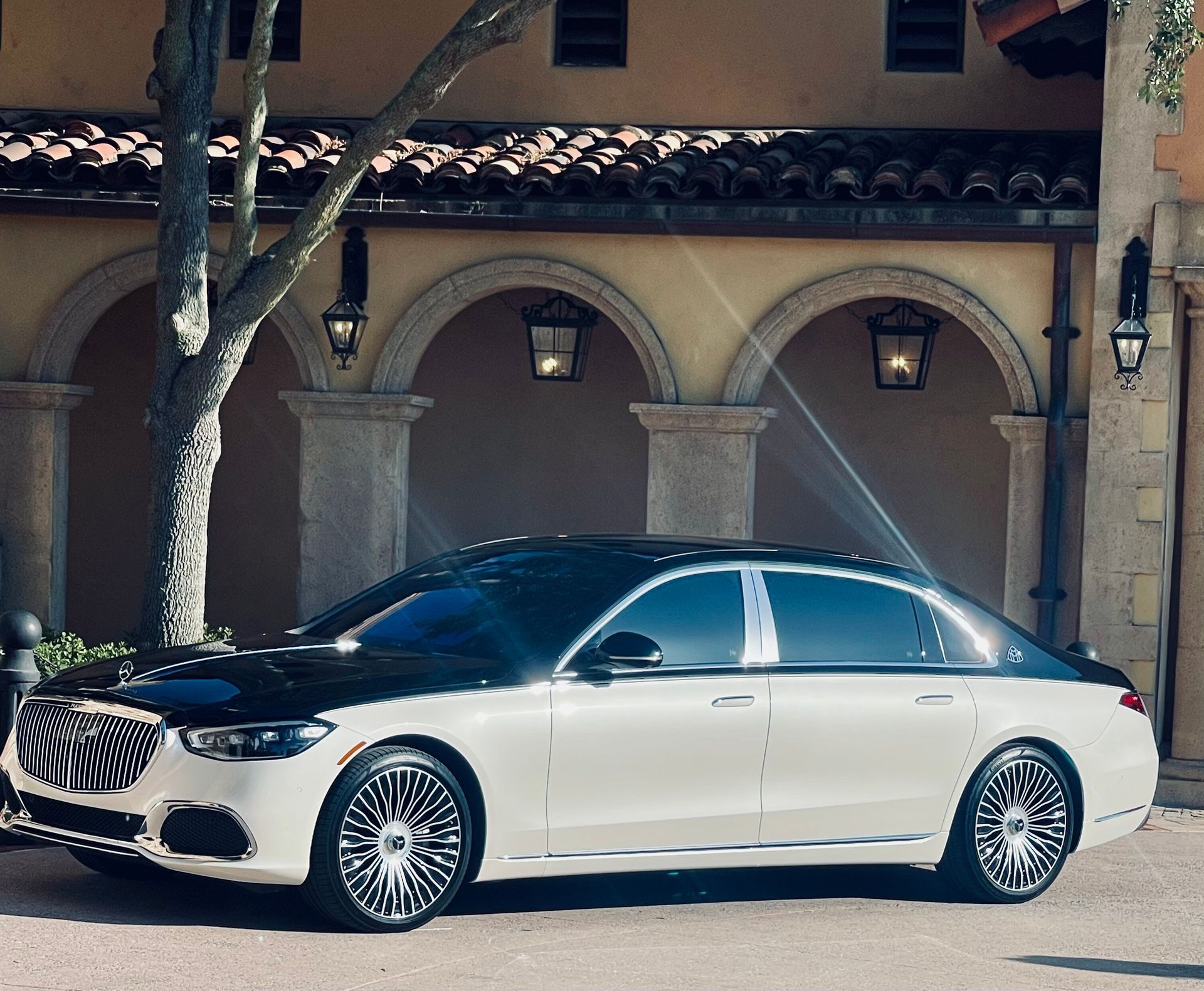 Exotic Limo Orlando White and black Mercedes-Maybach sedan parked in front of a building with arches and lanterns.