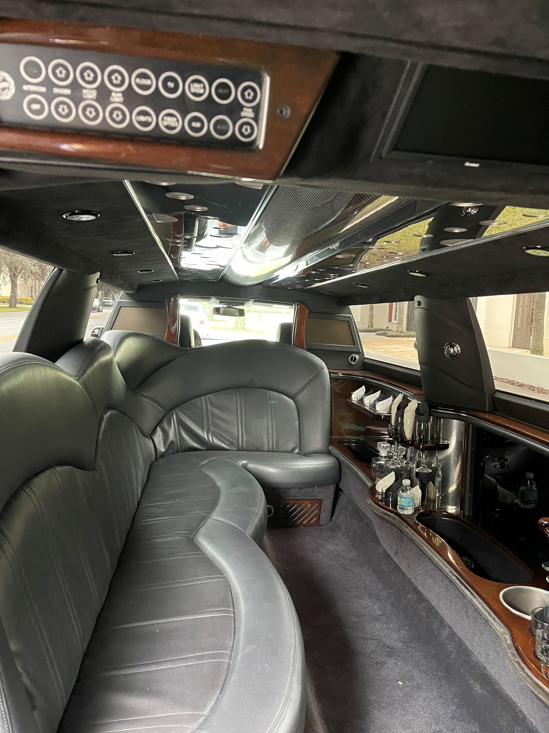 Exotic Limo Orlando Interior of a black limousine with leather seating, mirrored ceiling, and bar.