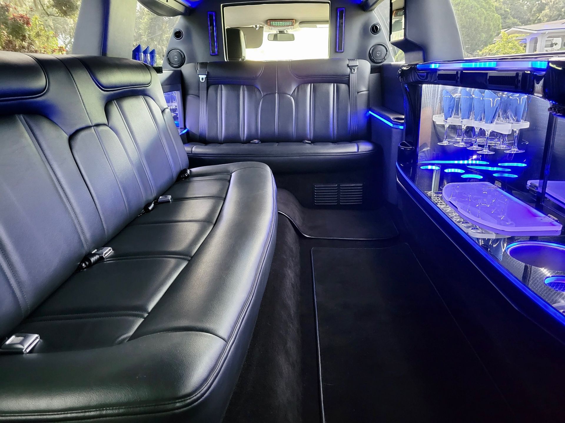 Exotic Limo Orlando Interior of a black limousine with leather seats, bar, and blue ambient lighting.