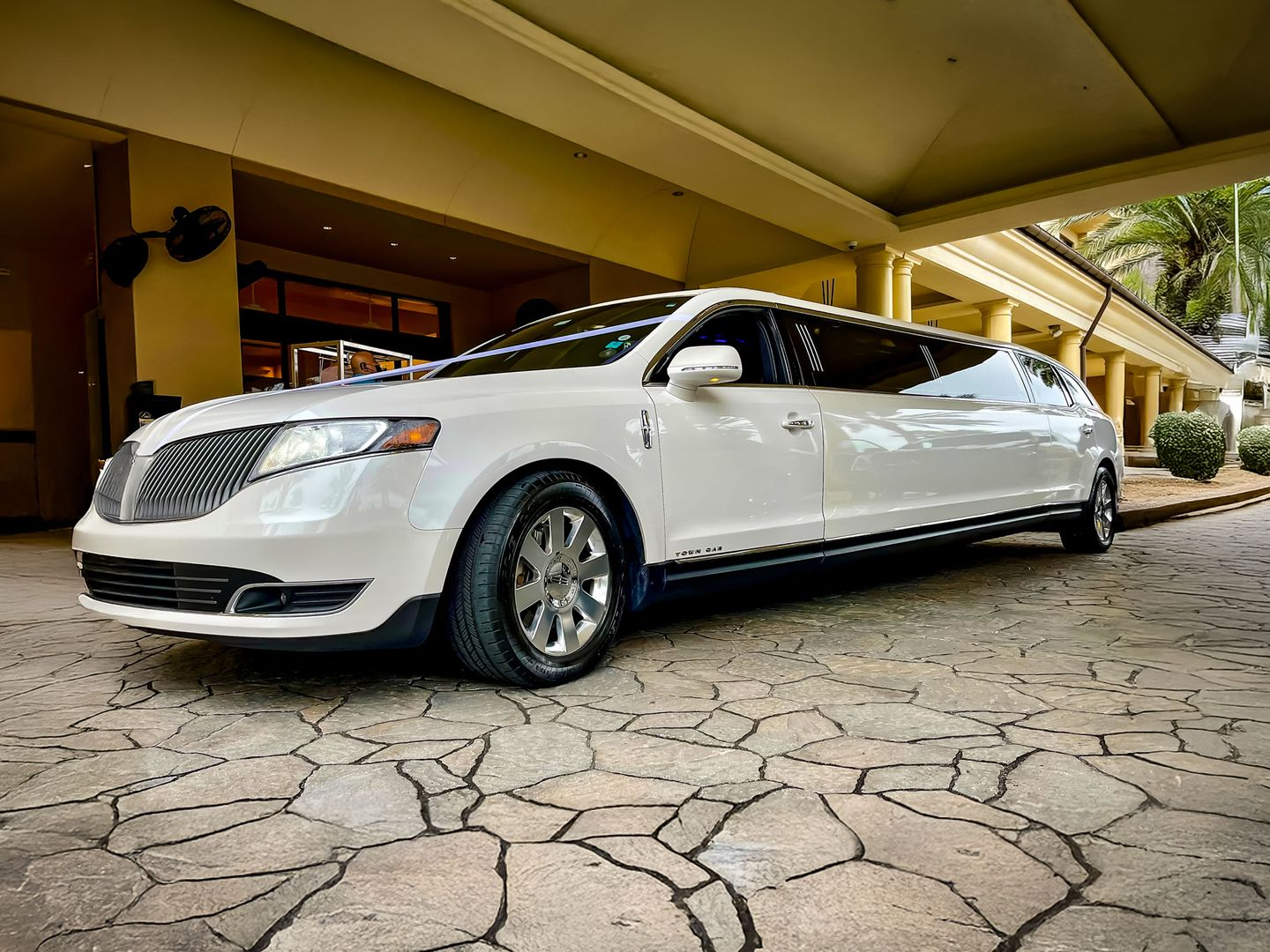 White limousine parked under a covered entryway with stone pavers.