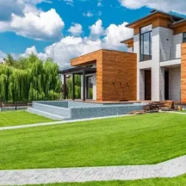 Brick house with white columns, front porch, and landscaped front walkway with shrubs.