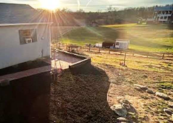 Sunlit backyard with a white shed, grassy field, and a long shadow at sunset