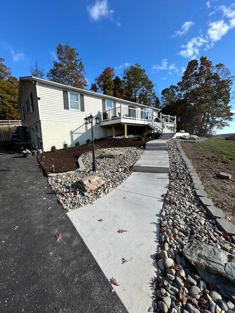 Single-story house with concrete accessible ramp and walkway in a landscaped yard under a blue sky