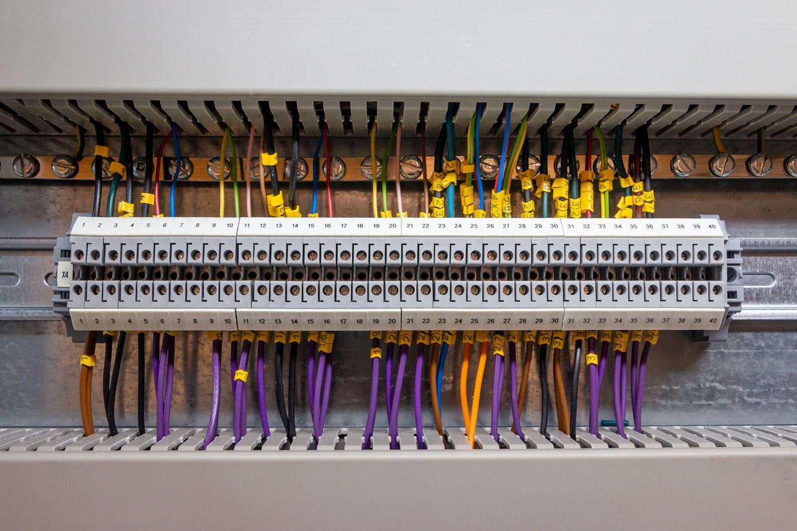 Hand working on electrical panel with colorful wires.