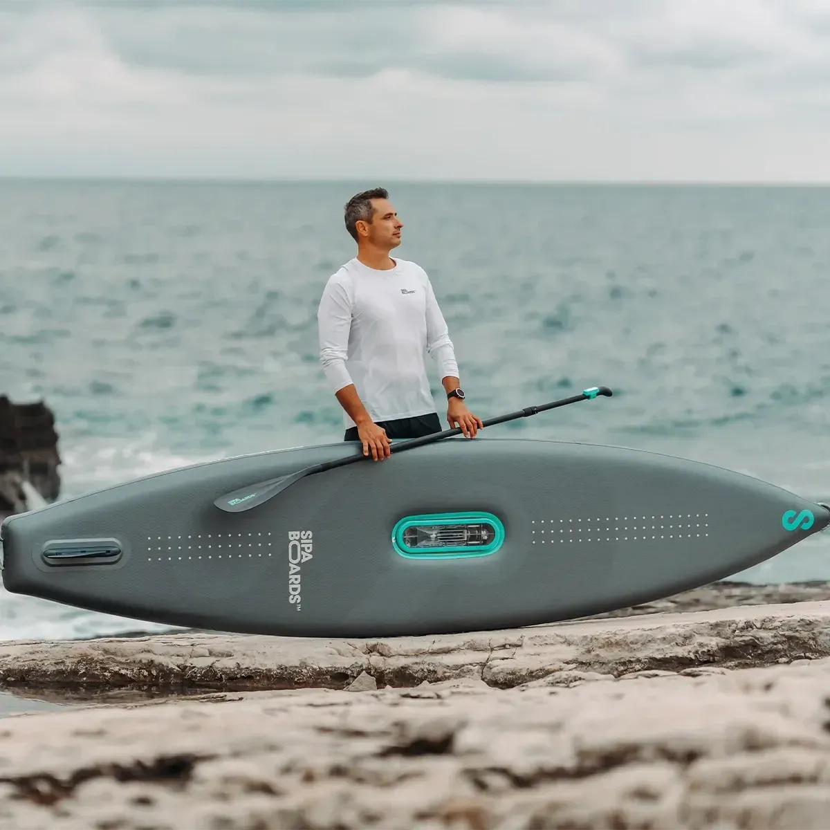 homme qui tient un sipaboard sur la plage