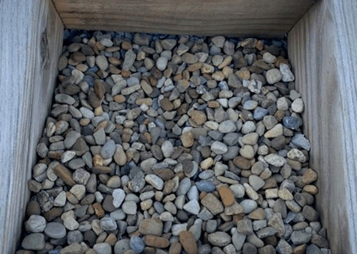 Small wooden box filled with assorted gray and tan pebbles