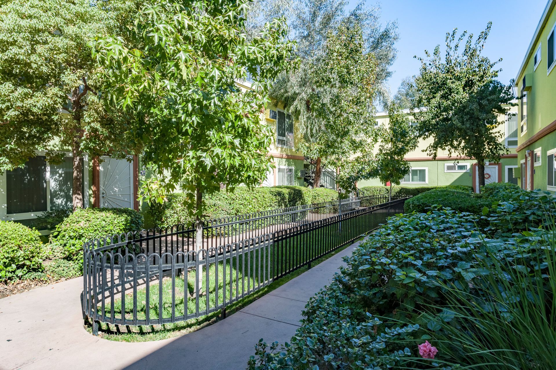 A fence surrounds a walkway between two buildings in a residential area.