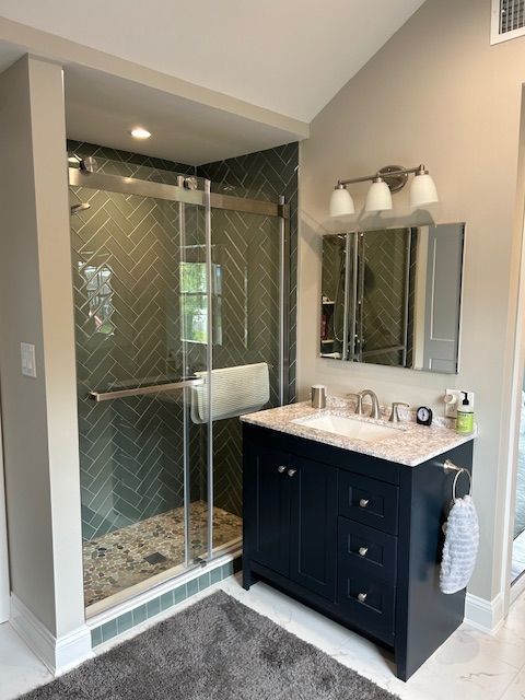 A bathroom with a sink a mirror and a walk in shower