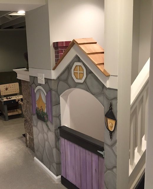 A playhouse in a basement with stairs leading up to it
