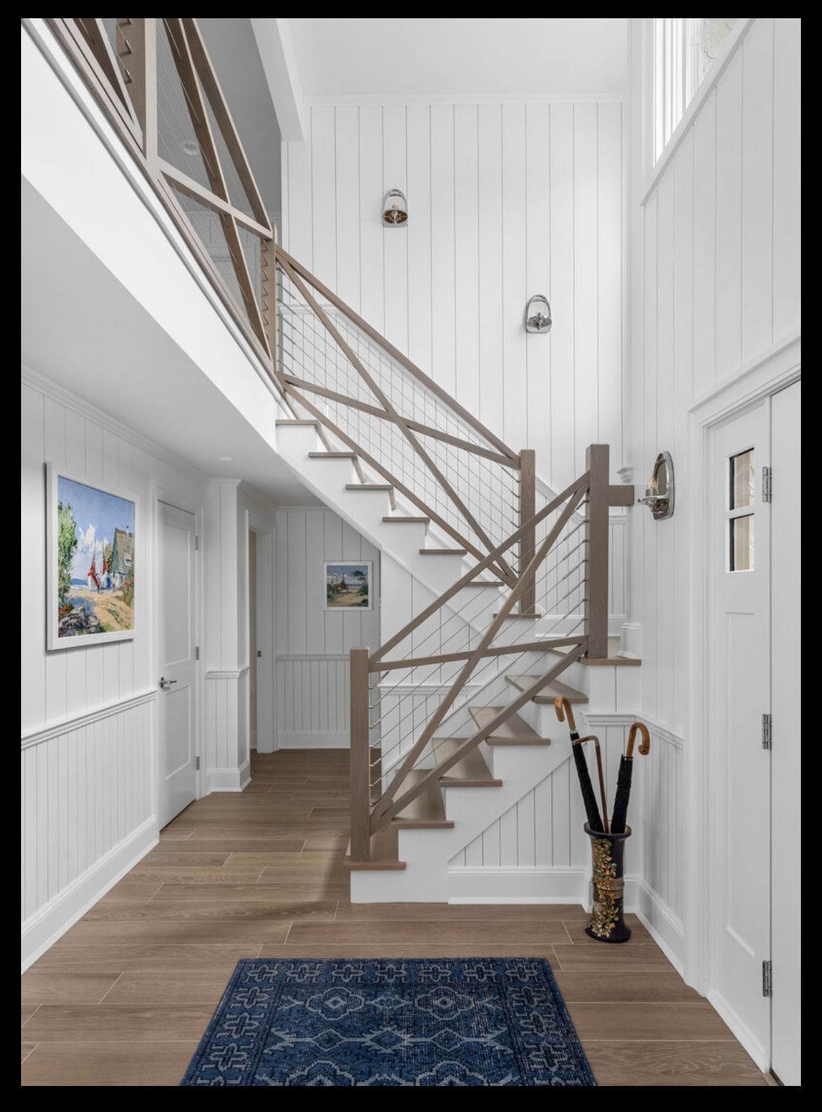 A hallway with a staircase and a picture on the wall.