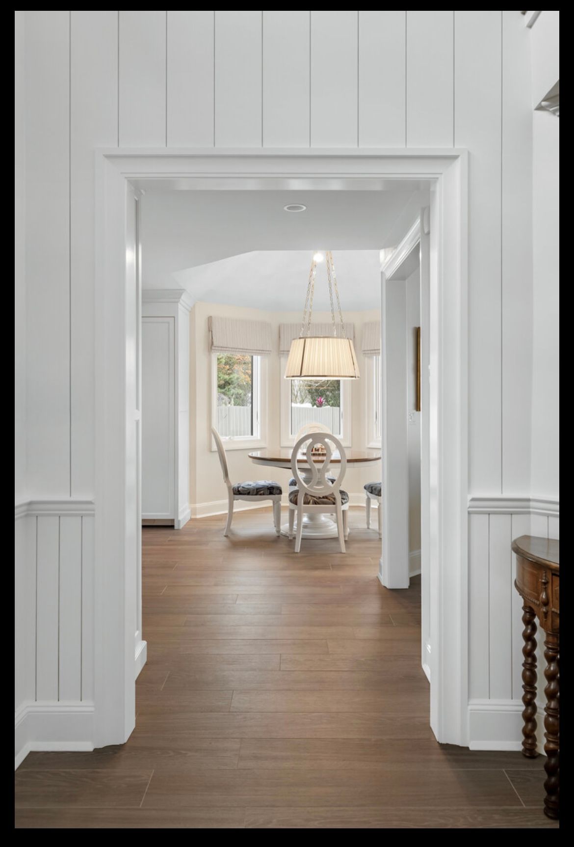 A hallway leading to a dining room with a table and chairs.