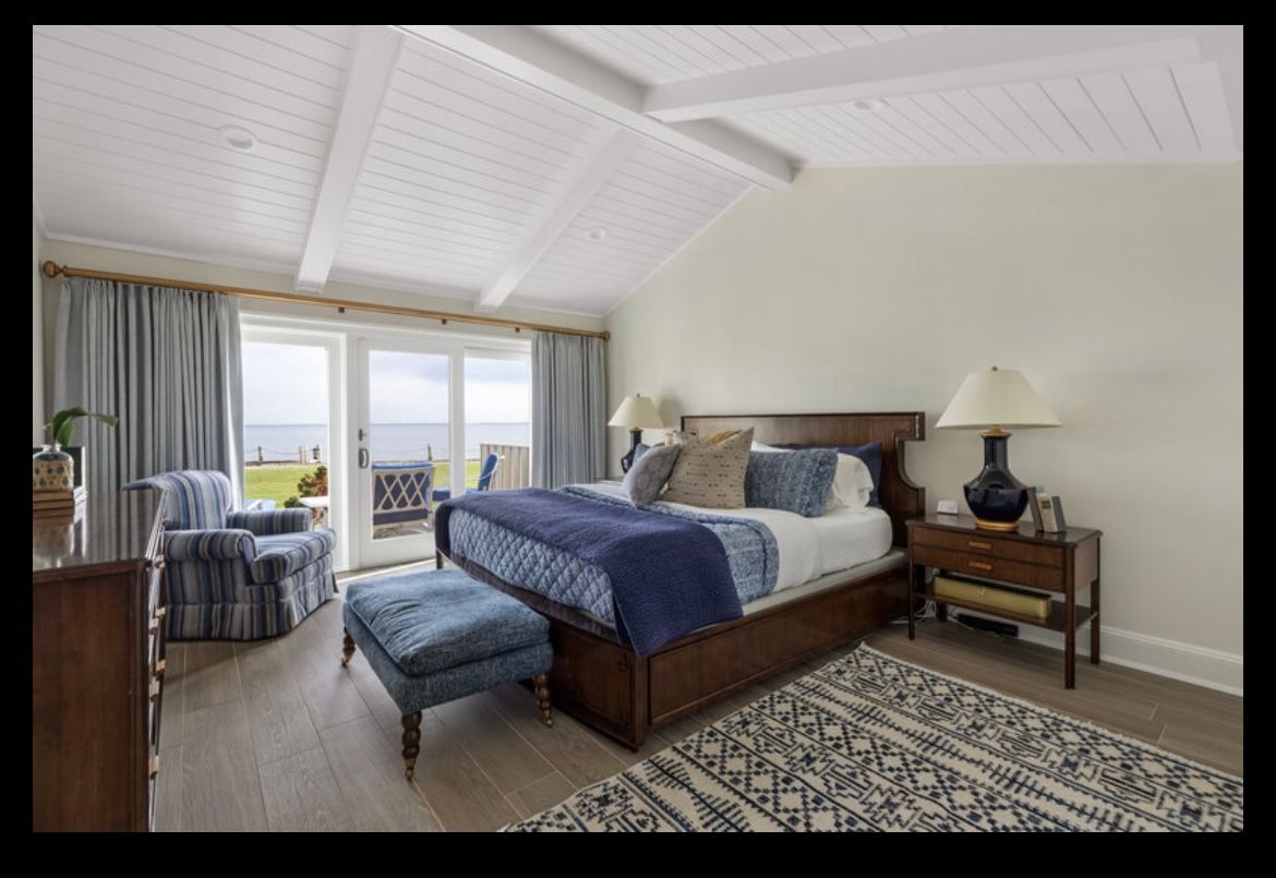 A bedroom with a king size bed , dresser , chair and lamps.