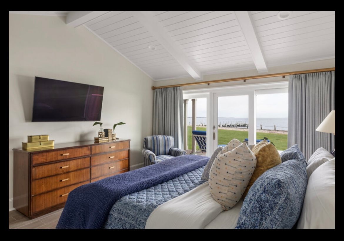 A bedroom with a large bed and a flat screen tv on the wall.