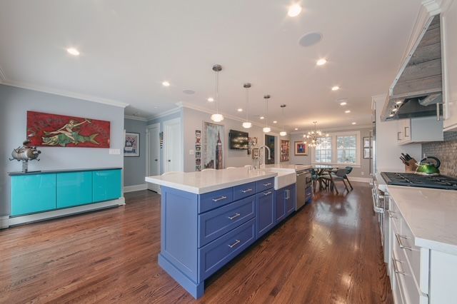 A kitchen with blue cabinets and a large island in the middle.