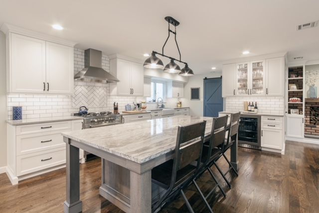 A kitchen with white cabinets and a large island in the middle.