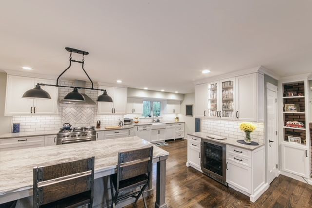 A kitchen with white cabinets , stainless steel appliances , a table and chairs.