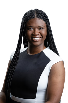 A woman with braids is wearing a black and white dress and smiling.