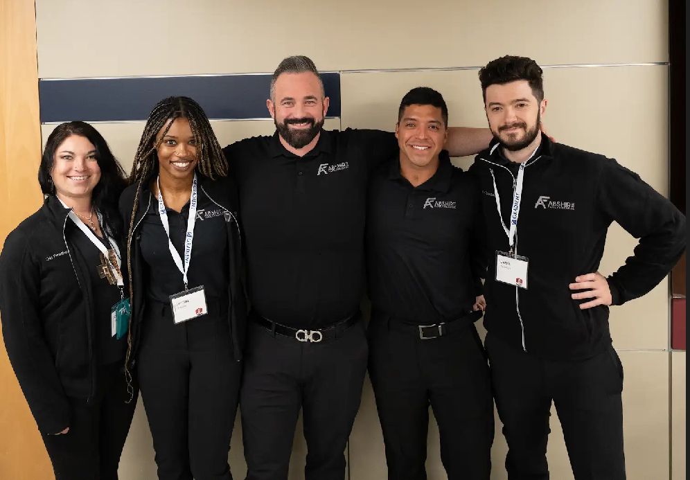 A man in a suit is sitting at a table with a tablet and a clipboard.