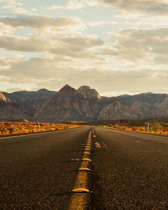 A road going through a desert with mountains in the background