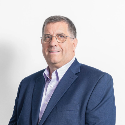 A man in a blue suit and glasses is smiling for the camera.