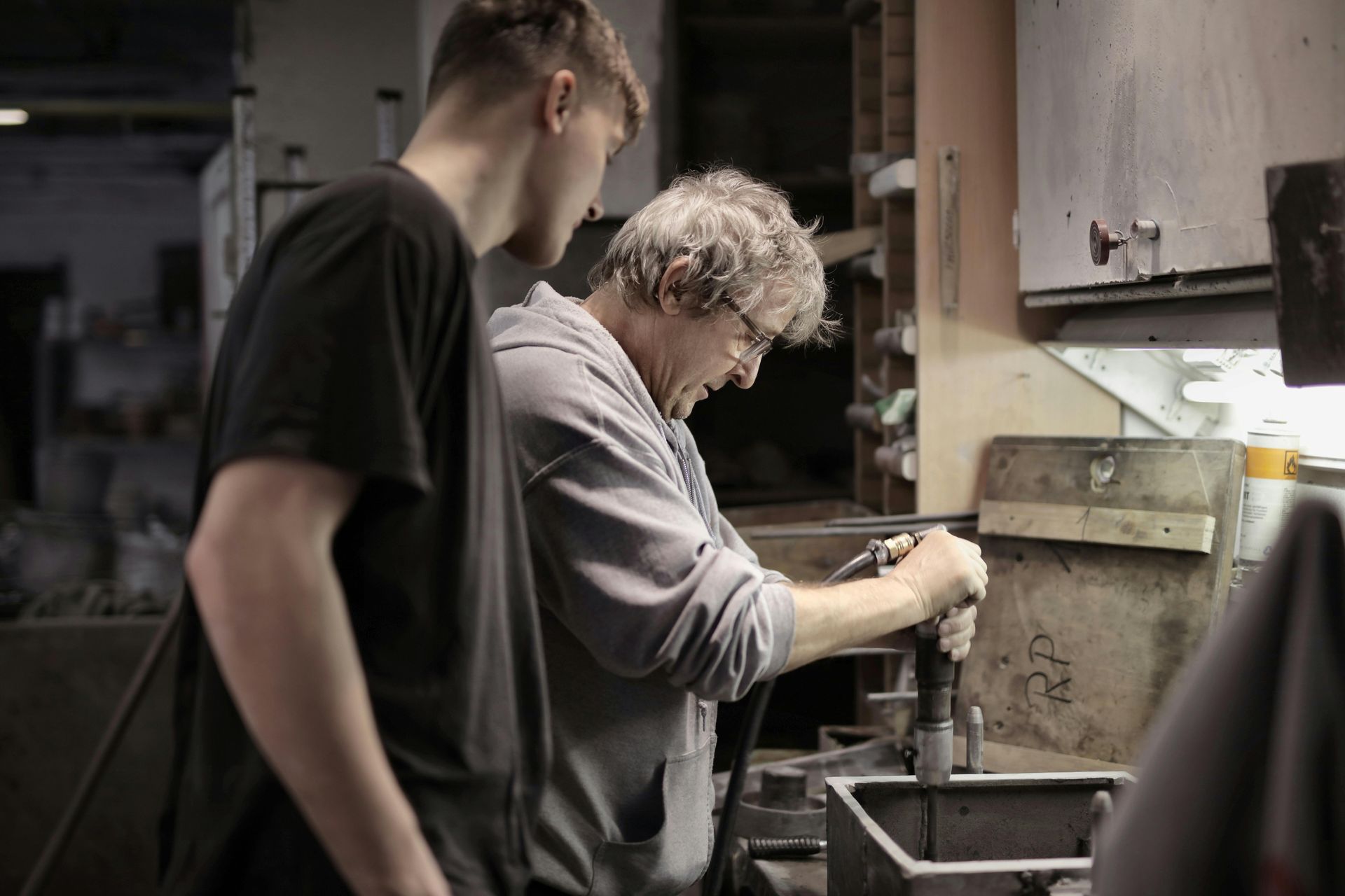 Two men are working on a machine in a workshop.