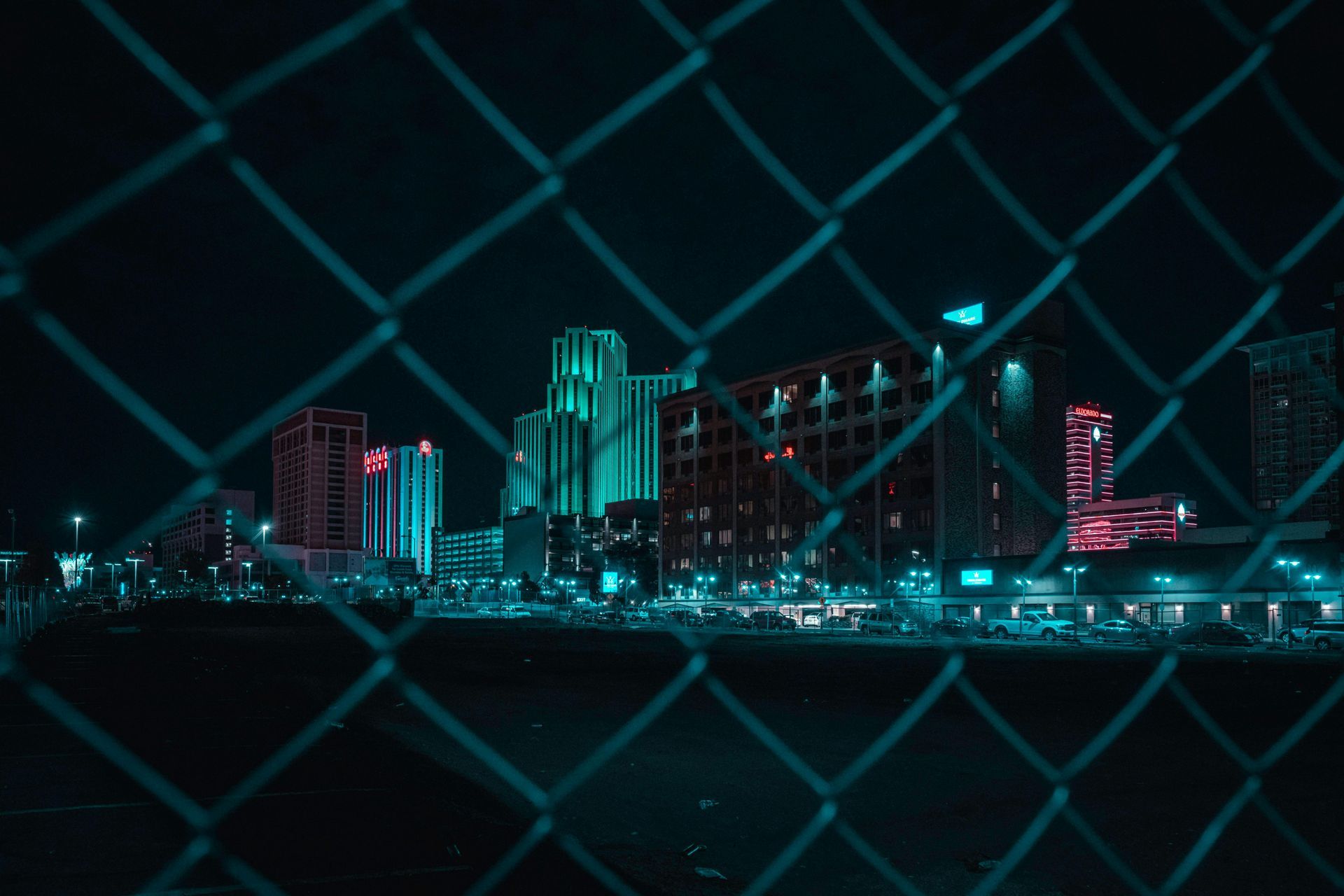 A chain link fence with a view of a city at night.