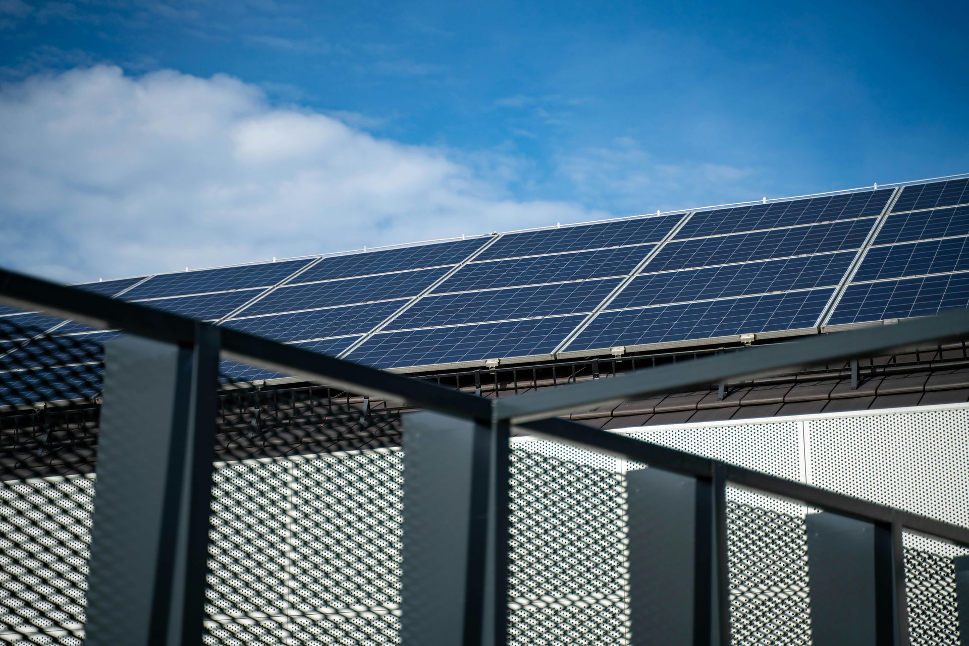Solar panels mounted on a metal fence against a blue sky