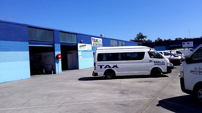 A White Tax Van is Parked in Front of a Building — Tweed Heads Coolangatta Taxi Service In Tweed Heads, NSW