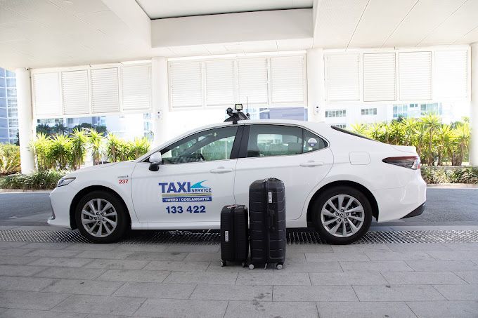A White Taxi is Parked Next to Two Suitcases — Tweed Heads Coolangatta Taxi Service In Tweed Heads, NSW