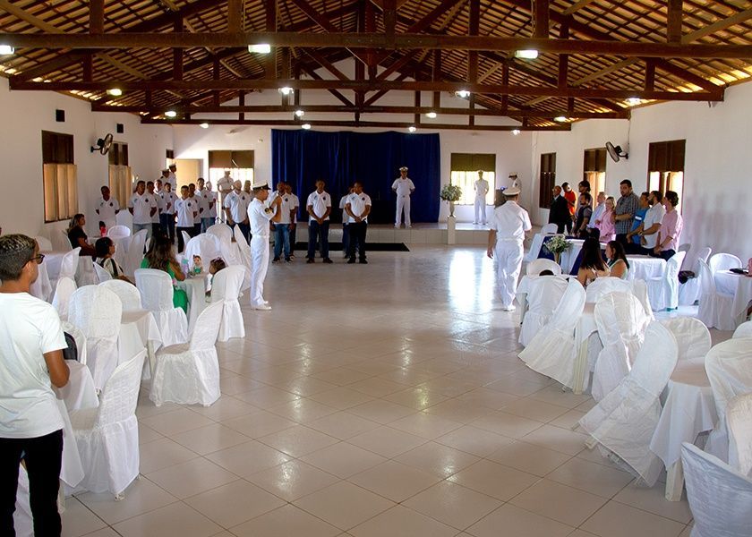 Uma grande sala com mesas e cadeiras preparadas para uma festa