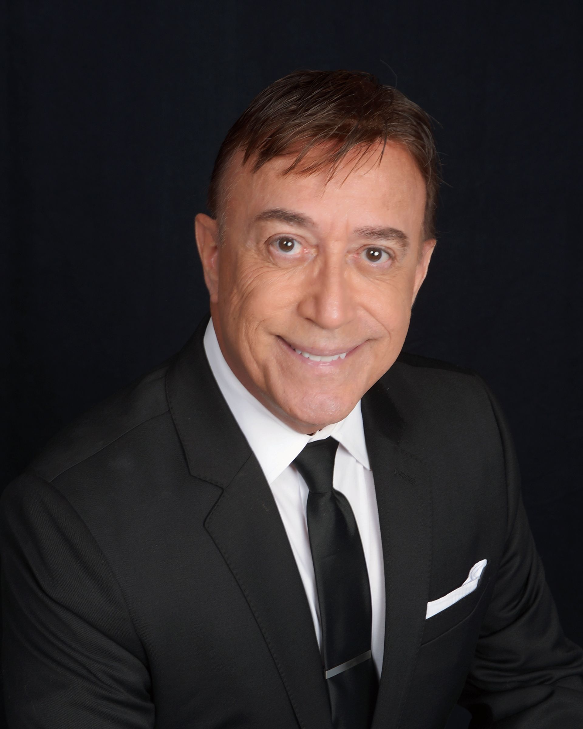 A man is sitting on a couch talking to two older people.