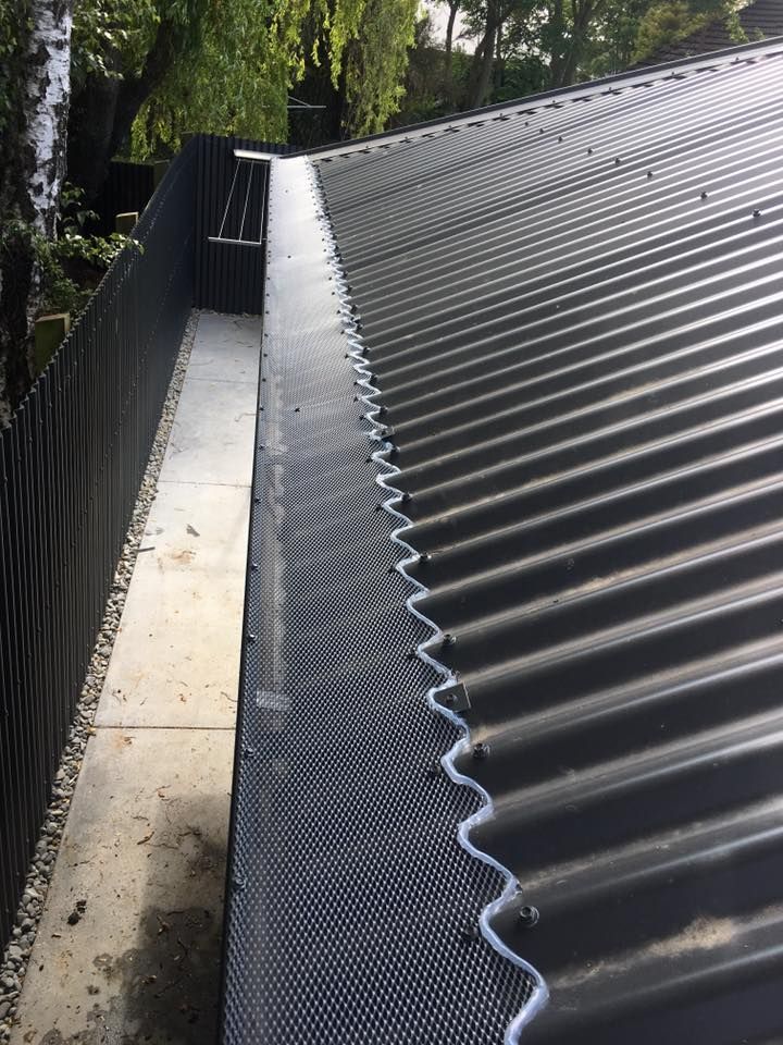 Black corrugated metal roof with installed gutter guard, seen from above.
