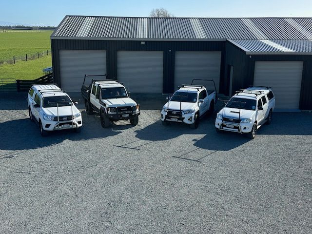 White pickup truck with roof racks parked near a lake and mountains. Truck has business name on side.