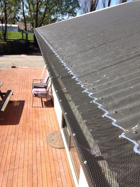 Black roof with gutter guards installed. The roof overlooks a wooden deck and outdoor seating.