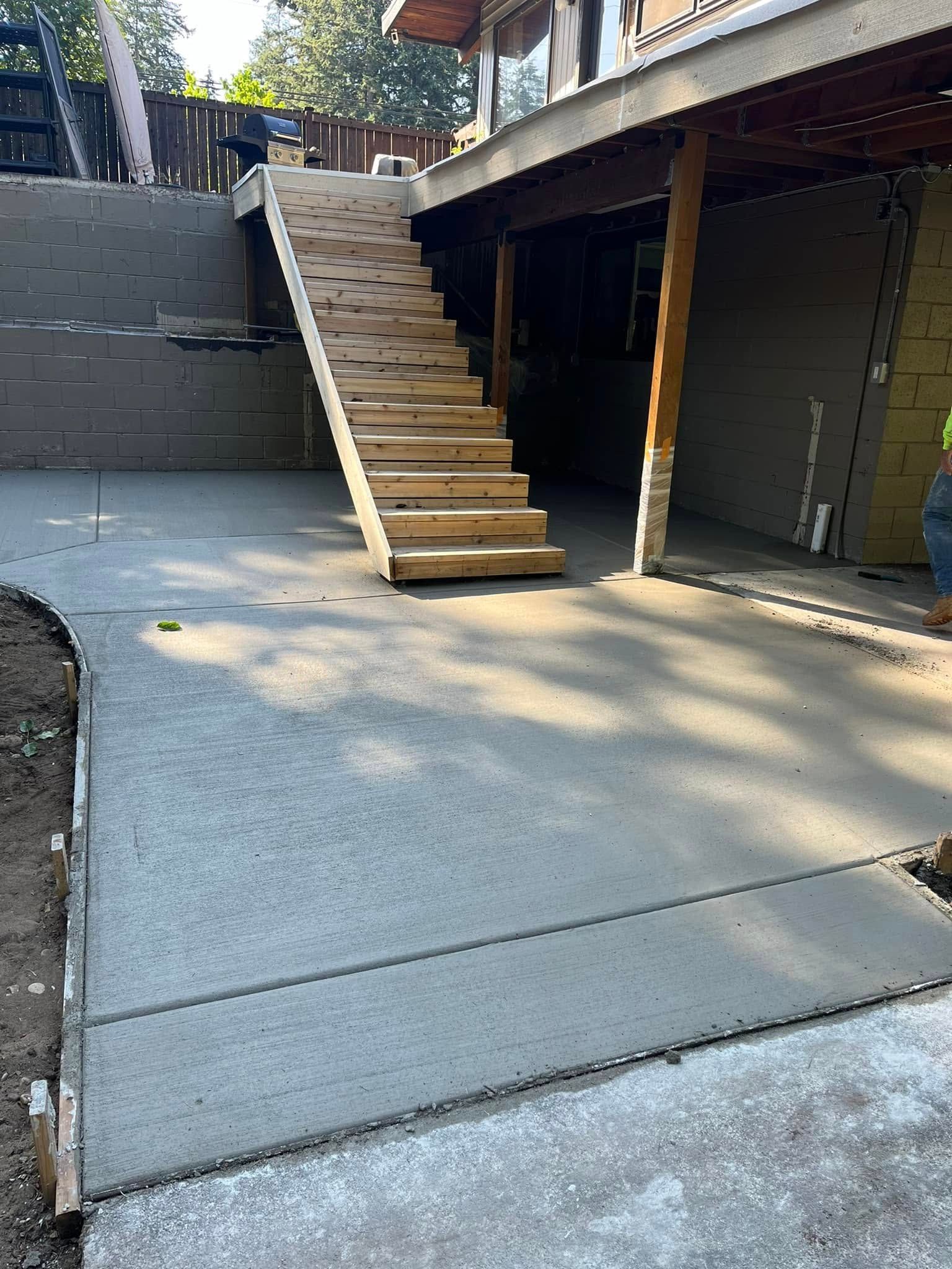 Newly poured concrete patio and stairs leading up to a house.