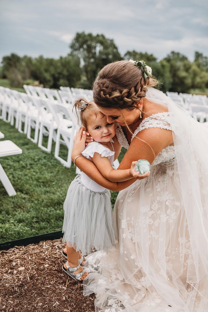 Bride hugs a young child. Wedding scene with rows of chairs in the background.