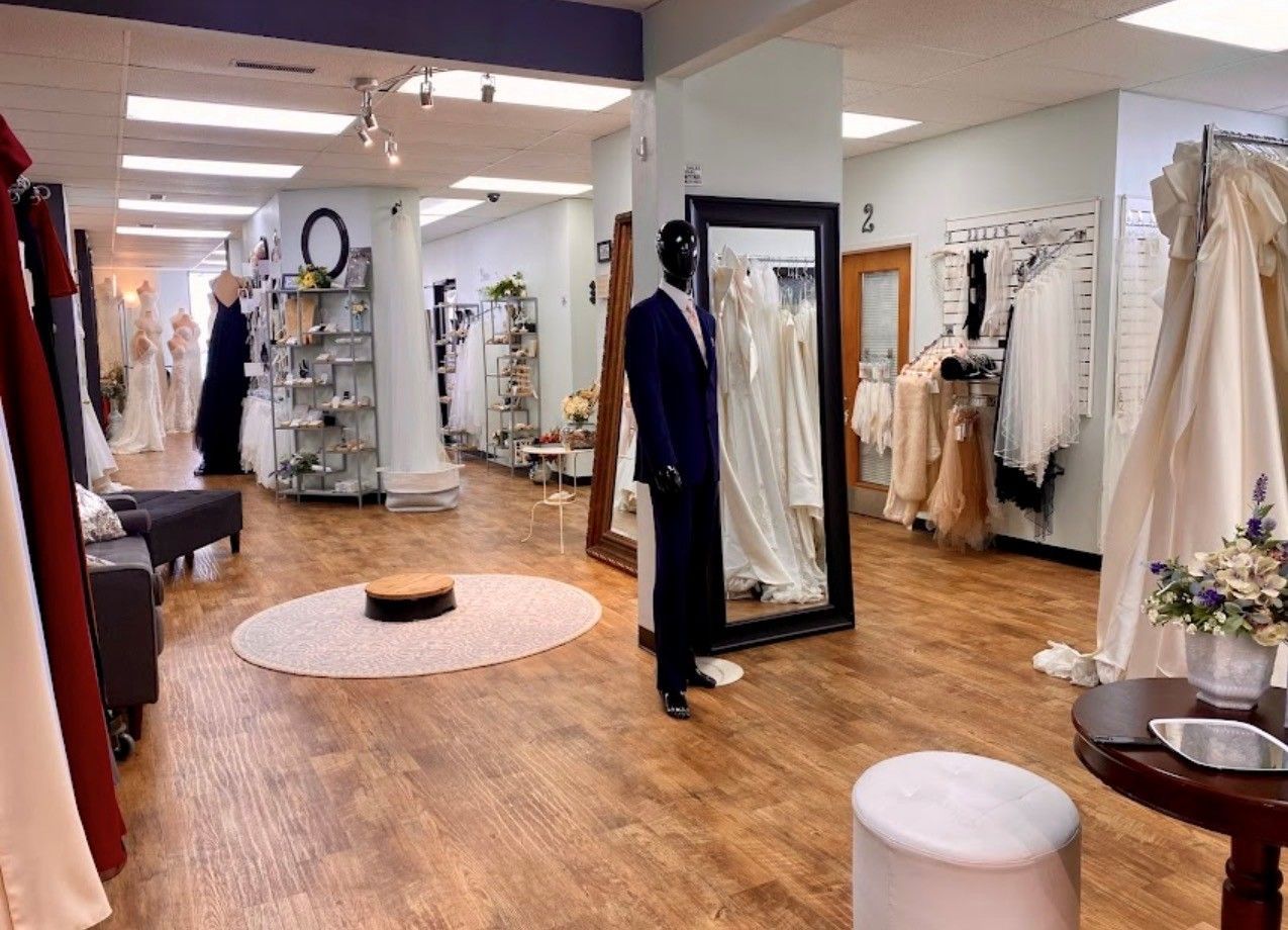 Wedding dress boutique interior with gowns on display, wood floors, and a mannequin.