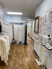 Bridal shop interior with dresses on racks, accessories on display, and wooden floors.