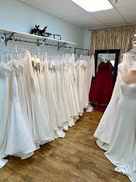 Wedding dresses displayed in a bridal shop, in various white and cream colors.