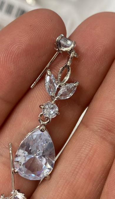 Silver dangling earring with clear teardrop and gemstone accents.
