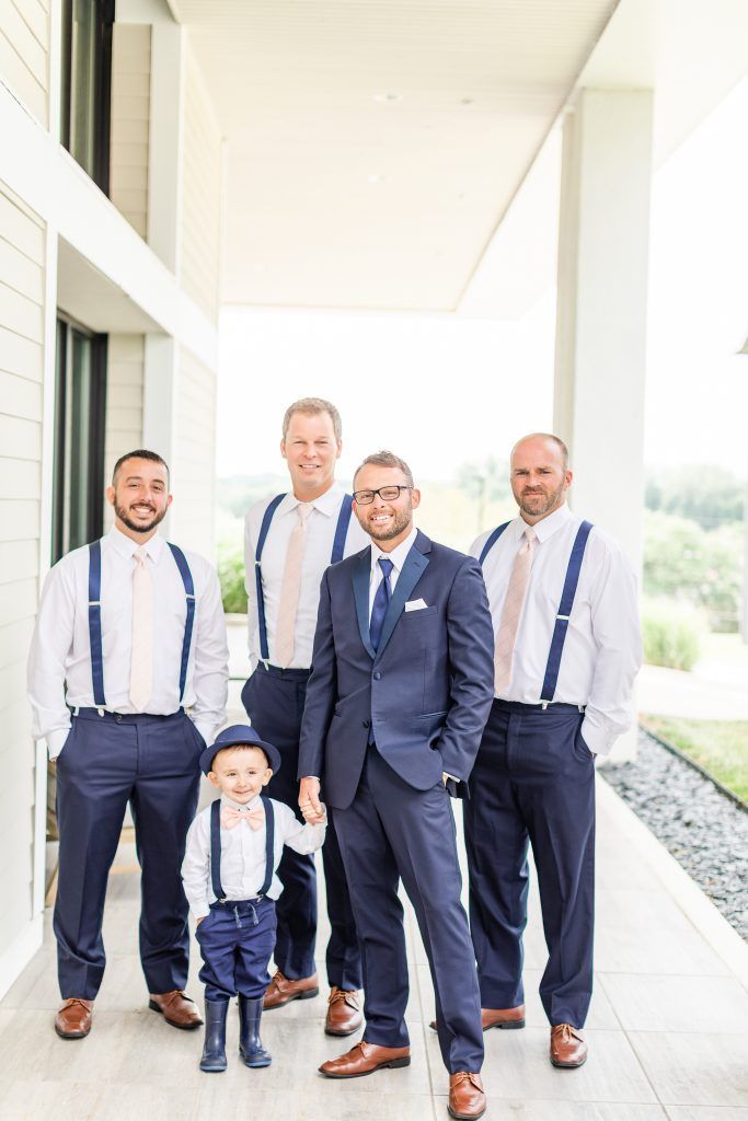 Group of men and a child in suits, holding hands, posing on a porch. Blue and pink attire.