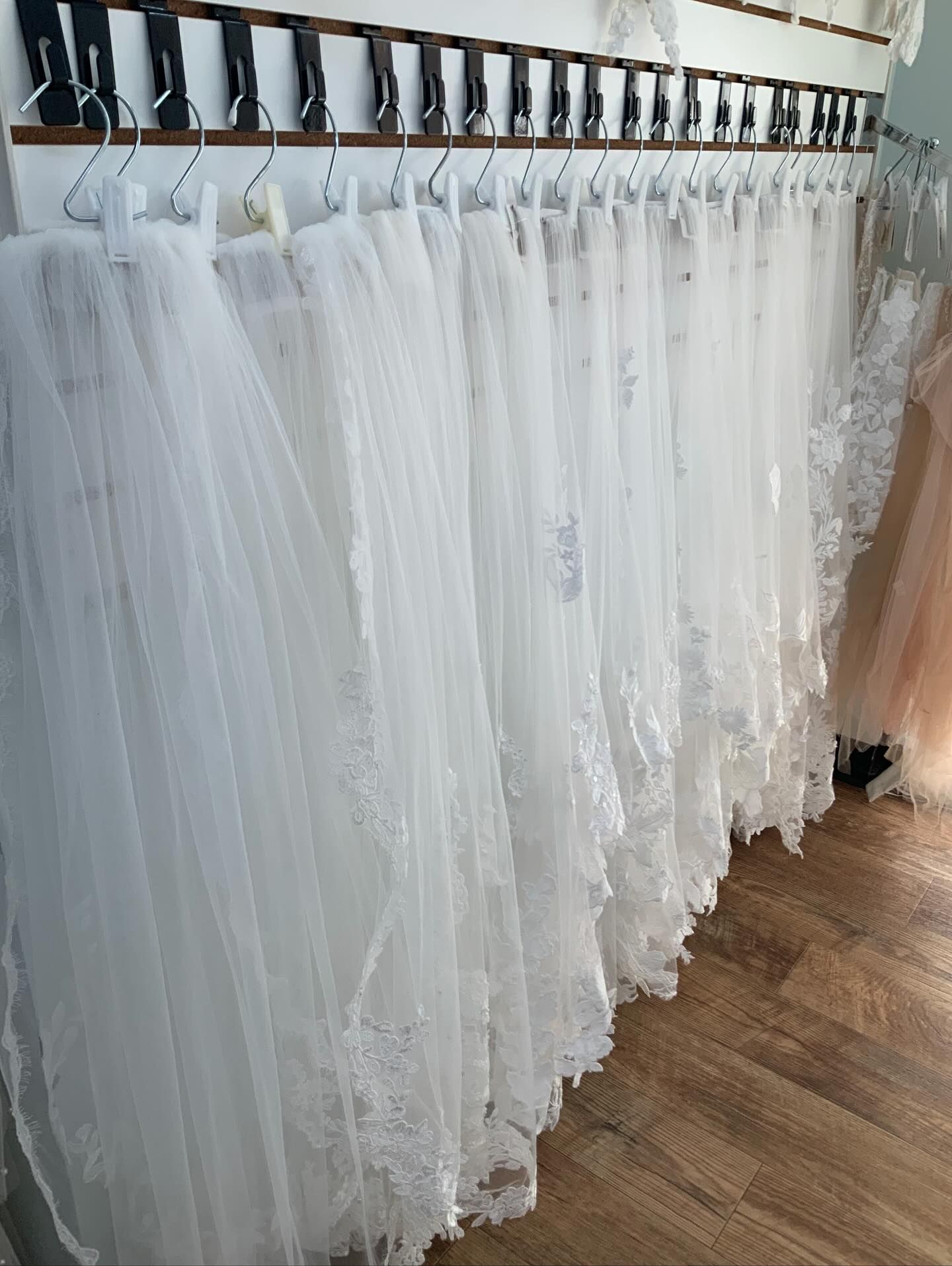 Woman in a white backless dress smiles, looking over her shoulder. Dark hair, red lipstick, near a building.