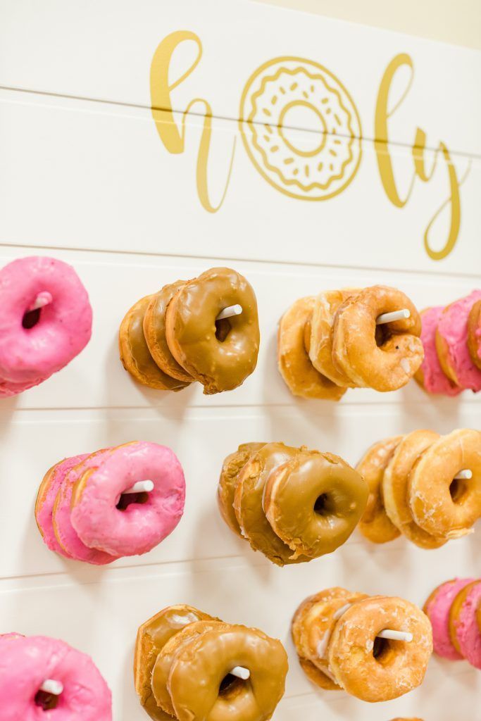 Donut wall with pink, brown, and plain donuts. Gold