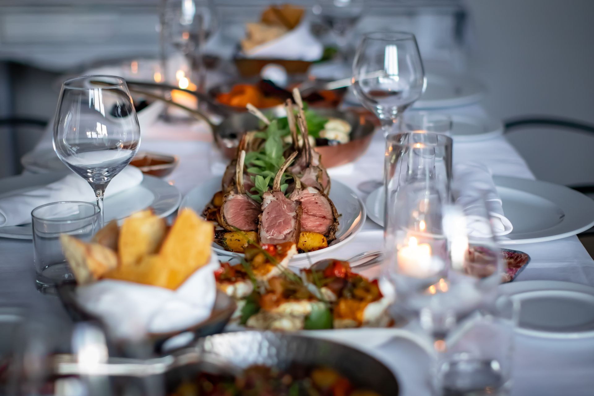 Long Table Topped With Plates of Food and Wine Glasses