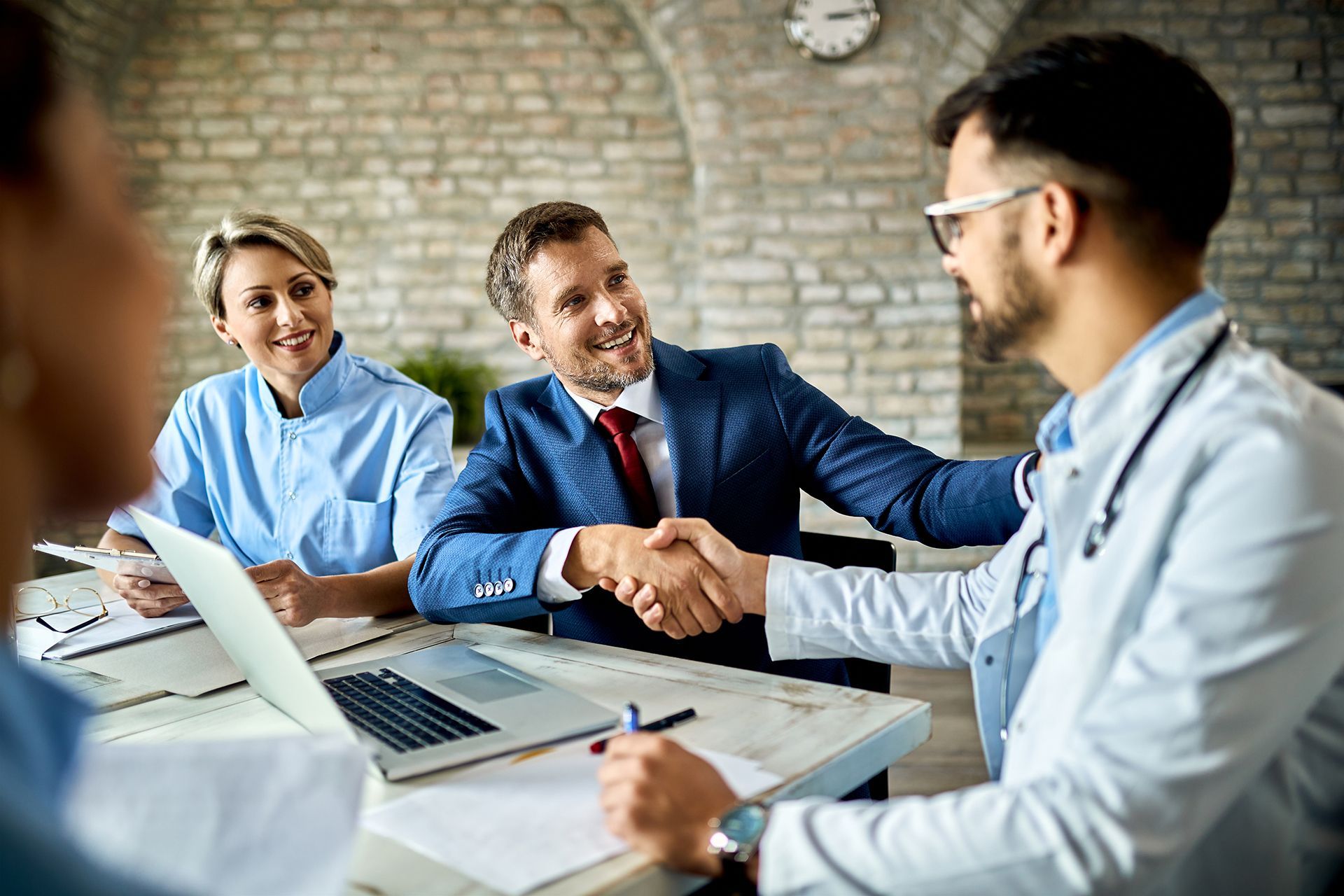 A doctor is shaking hands with a businessman during a meeting.